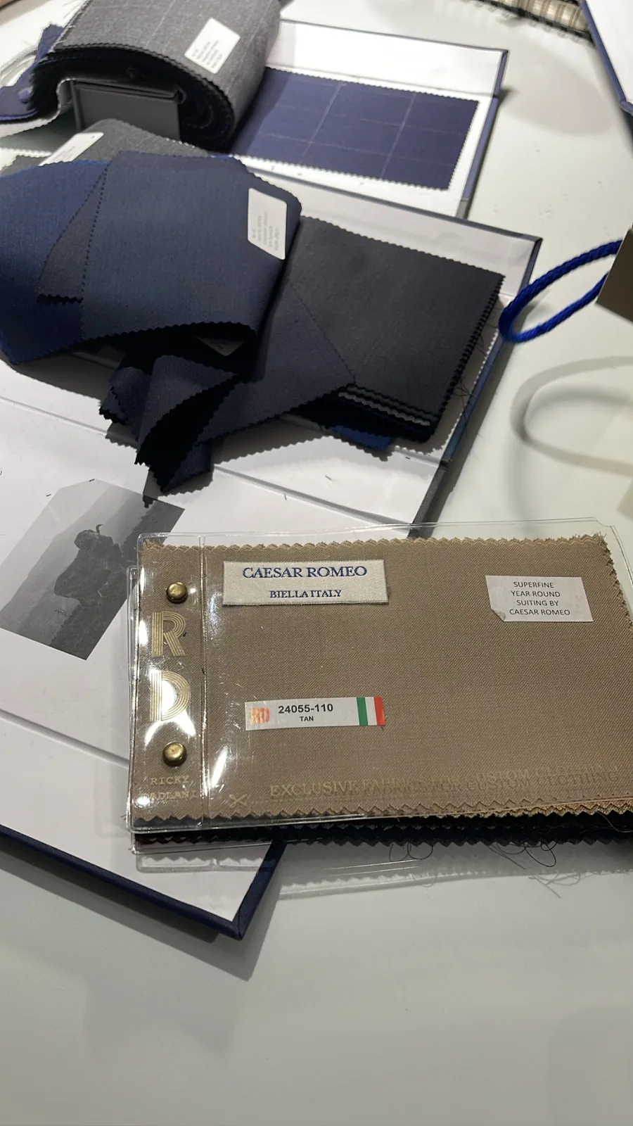 Open fabric books on the table, a swatch card from the Italian mill Reda resting on navy suiting
