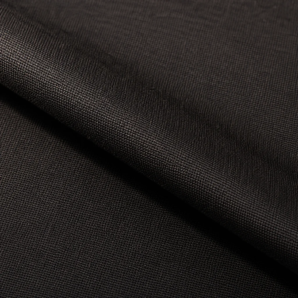 Close macro of finely woven very dark charcoal wool, folded once so the weave and its restrained sheen are visible