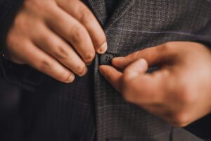 A man in a dark business suit buttoning a button on jacket